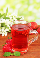 Delicious strawberry tea on table on bright background