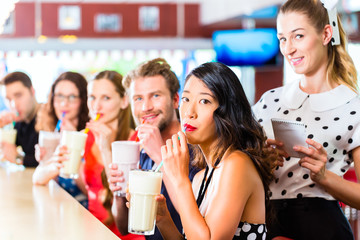 People in American diner or restaurant with milk shakes