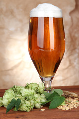 Glass of beer and hops, on wooden table