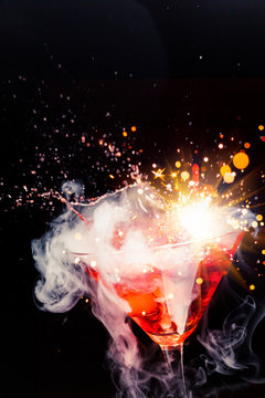 red cocktail with splash, sparkler and ice vapor