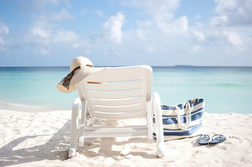 un lounge on a beach with hat and bag