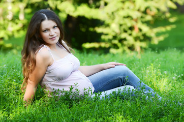 Naklejka na ściany i meble The pregnant woman in the summer on a grass