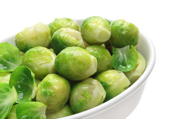 Cooked brussels sprouts in bowl on white background