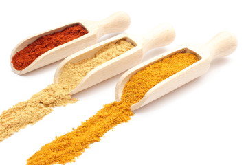 Three spices - curry, ginger and paprika - on wooden spoons