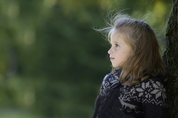 Naklejka premium little girl seated against a tree