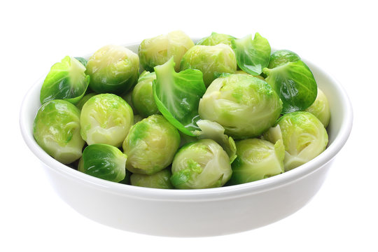 Cooked brussels sprouts in bowl on white background