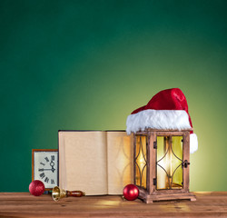 christmas hat, lantern, book and clock on a green vintage backgr