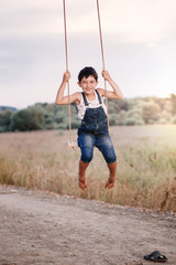 Happy young boy playing on swing in a park