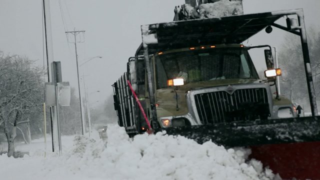Snow plow pushing snow pile to curb during blizzard