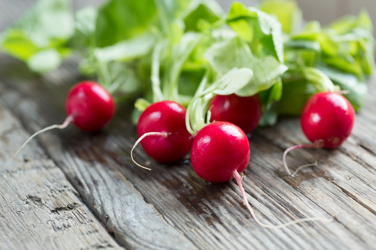 red radish with leaves on wooden table - ravanelli