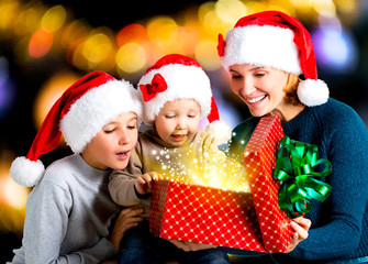 Fototapeta na wymiar Mother with children opens the box with gifts on the christmas h