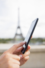 Woman in Paris using her cell phone in front of Eiffel Tower