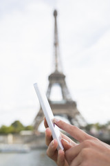 Woman in Paris using her cell phone in front of Eiffel Tower