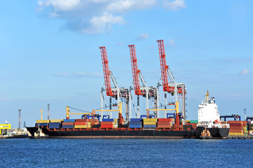 Fototapeta premium Tugboat assisting container cargo ship to harbor quayside