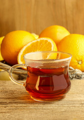 Glass of hot steaming tea among christmas decorations on wooden