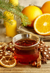 Glass of hot steaming tea among christmas decorations on wooden