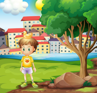 A boy with a rubber duck above his head standing near the tree