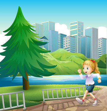 A girl running at the riverbank with a tall pine tree