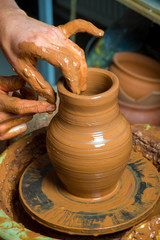 hands of a potter, creating an earthen jar on the circle