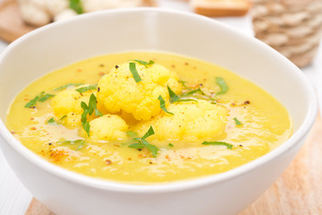 cauliflower soup with curry and cream in a bowl, close-up