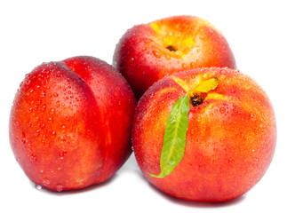 Ripe nectarine with a green leaf in water drops 