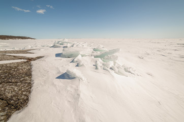 Snow, ice, hummocks on snow-covered ice of lake. A natural winte