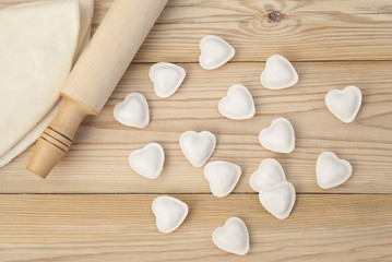 Fototapeta na wymiar Dumplings in a heart shape dough and rolling pin.