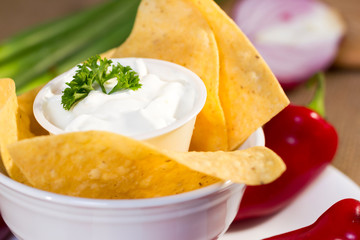 Sourcream with corn chips and red hot chilli peppers.