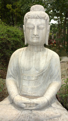 Ancient Buddha statue against green woods