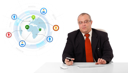 businessman sitting at desk and holding a mobilephone with globe