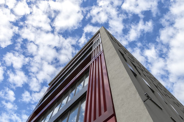 Fototapeta na wymiar Hochhaus vor blauem Himmel mit vielen Wolken