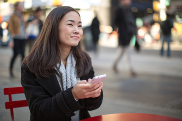 Asian woman in New York City texting cellphone