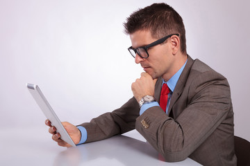 side of young business man looking pensively at his tablet