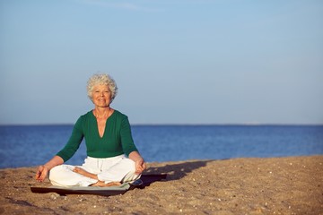 Senior woman meditating on beautiful beach