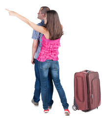 young couple traveling with suitcas and pointing at wal Back vie