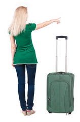 Back view of young blonde woman traveling with suitcas and point