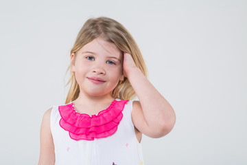 A little girl in a dress with butterflies corrects blond hair