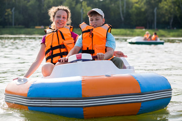 Son and mother in life jackets floating down the river in boat