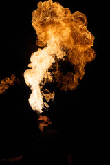 Fakir breathes spurts of flame in the dark