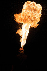 Fakir breathes spurts of fire in the dark