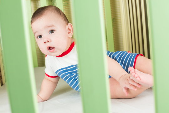 Baby Boy In Crib Looking Through A Safety Fence