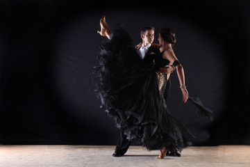 Latino dancers in ballroom against on black background