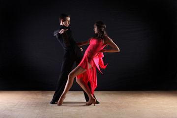 Latino dancers in ballroom against on black background