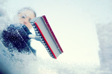 winter driving - scraping ice from a windshield