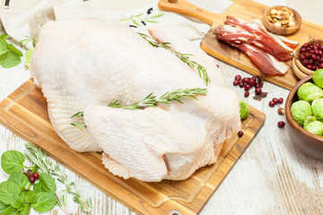 Whole raw turkey on wooden cutting board,vegetables, ham,spices