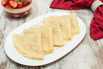 Several thin pancakes, with ingredients,  on a plate