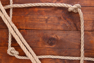 Fototapeta na wymiar Frame composed of rope on wooden background