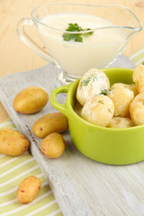 Tender young potatoes with sour cream and herbs in pan