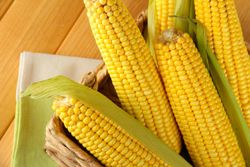 Crude corns in basket on napkin on wooden table