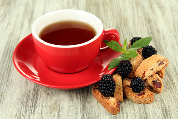 Cup of tea with cookies and blackberry on table close-up